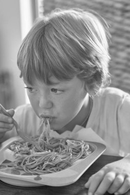 5 yaşında erkek çocuk domates soslu spagetti yiyor.