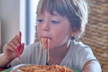 5 yaşında erkek çocuk domates soslu spagetti yiyor.