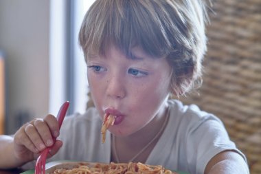 5 yaşında erkek çocuk domates soslu spagetti yiyor.