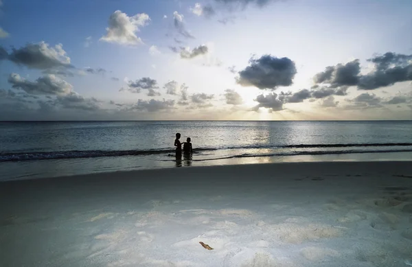 Crianças brincando na água do mar ao pôr do sol — Fotografia de Stock