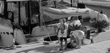 İtalya, Sicilya, Akdeniz, Marina di Ragusa (Ragusa Eyaleti); 7 Ekim 2025, limanda insanlar ve bir katamaran yelkenli teknesi - EDITORIAL