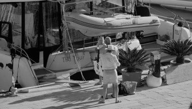 İtalya, Sicilya, Akdeniz, Marina di Ragusa (Ragusa Eyaleti); 7 Ekim 2025, limanda insanlar ve bir katamaran yelkenli teknesi - EDITORIAL