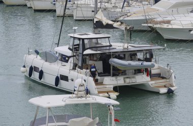 İtalya, Sicilya, Akdeniz, Marina di Ragusa (Ragusa Eyaleti); 30 Ekim 2025, limandaki katamaran yelkenli teknesinde insanlar - EDITORIAL