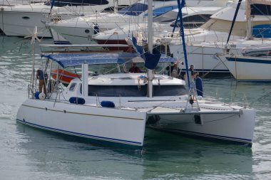 İtalya, Sicilya, Akdeniz, Marina di Ragusa (Ragusa Eyaleti); 7 Kasım 2025, limandaki katamaran yelkenli teknesinde erkekler - EDITORIAL