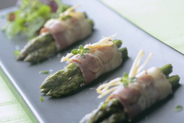 İtalya, Roma, yemek; kuşkonmaz mızrakları siyah tabakta tütsülenmiş pastırmaya sarılmış.