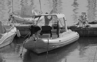 İtalya, Sicilya, Akdeniz, Marina di Ragusa (Ragusa ili); 13 Aralık 2025, limanda bir kauçuk teknede çift - EDITORIAL