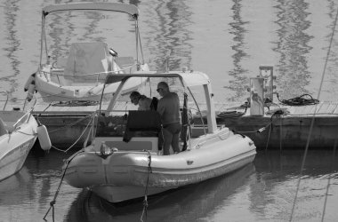 İtalya, Sicilya, Akdeniz, Marina di Ragusa (Ragusa ili); 13 Aralık 2025, limanda bir kauçuk teknede çift - EDITORIAL