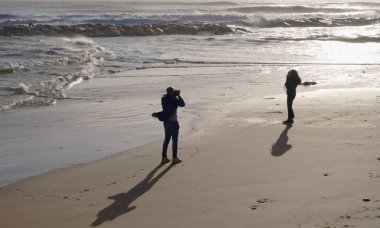 İtalya, Sicilya, Akdeniz, Marina di Ragusa (Ragusa Eyaleti), sahilde bir kadının fotoğraflarını çeken fotoğrafçı.