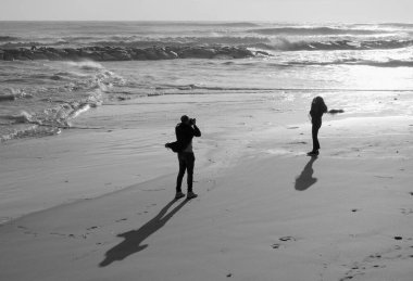 İtalya, Sicilya, Akdeniz, Marina di Ragusa (Ragusa Eyaleti), sahilde bir kadının fotoğraflarını çeken fotoğrafçı.