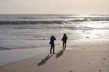 İtalya, Sicilya, Akdeniz, Marina di Ragusa (Ragusa Eyaleti), sahilde bir kadının fotoğraflarını çeken fotoğrafçı.