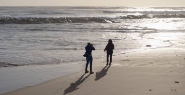 İtalya, Sicilya, Akdeniz, Marina di Ragusa (Ragusa Eyaleti), sahilde bir kadının fotoğraflarını çeken fotoğrafçı.