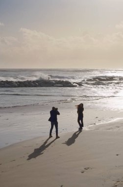 İtalya, Sicilya, Akdeniz, Marina di Ragusa (Ragusa Eyaleti), sahilde bir kadının fotoğraflarını çeken fotoğrafçı.