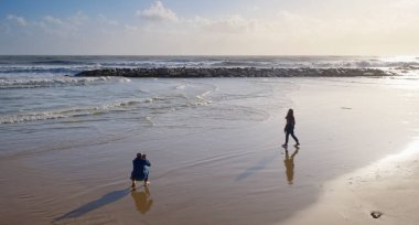 İtalya, Sicilya, Akdeniz, Marina di Ragusa (Ragusa Eyaleti), sahilde bir kadının fotoğraflarını çeken fotoğrafçı.
