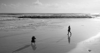 İtalya, Sicilya, Akdeniz, Marina di Ragusa (Ragusa Eyaleti), sahilde bir kadının fotoğraflarını çeken fotoğrafçı.