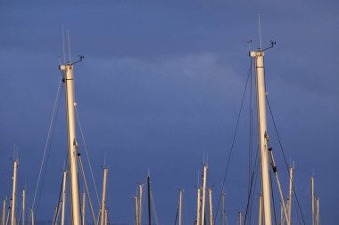 İtalya, Sicilya; Marina di Ragusa (Ragusa Eyaleti); gün batımında limanda yelkenli gemi direkleri