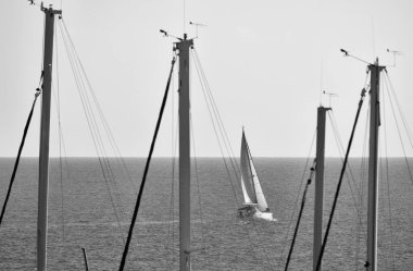 İtalya, Sicilya, Akdeniz, Marina di Ragusa (Ragusa Eyaleti), limanda yelkenli direkleri ve arka planda bir yelkenli.