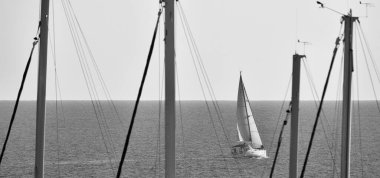 İtalya, Sicilya, Akdeniz, Marina di Ragusa (Ragusa Eyaleti), limanda yelkenli direkleri ve arka planda bir yelkenli.