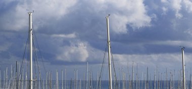 İtalya, Sicilya, Akdeniz, Marina di Ragusa (Ragusa Eyaleti); limanda yelkenli gemi direkleri ve arka planda bulutlar