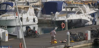 İtalya, Sicilya, Akdeniz, Marina di Ragusa (Ragusa Eyaleti); 6 Ocak 2025, limandaki insanlar ve lüks yatlar - EDITORIAL