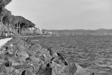 İtalya, Bracciano Gölü, Trevignano (Roma), volkanik göl manzarası ve gezinti güvertesinde yürüyen insanlar