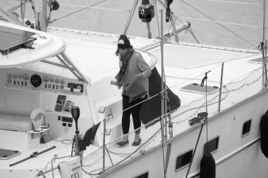 İtalya, Sicilya, Akdeniz, Marina di Ragusa (Ragusa Eyaleti); 16 Şubat 2026, limandaki bir katamaran yelkenli teknesinde kadın - EDITORIAL