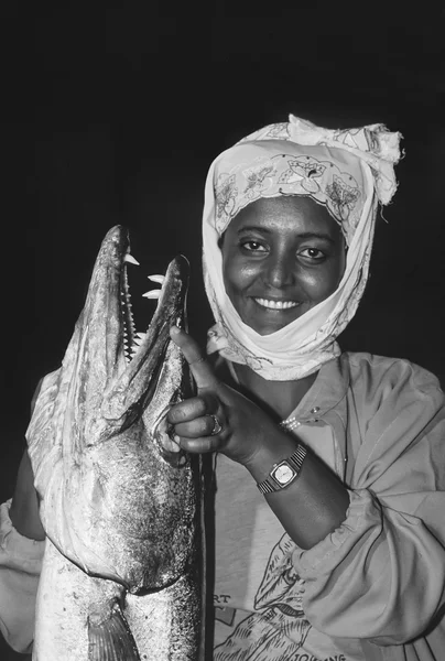 SUDAN, Faro del Arrecife de Sanghaneb; 13 de noviembre de 2002, Mujer sudanesa vestida con traje tradicional que sostiene una Gran Barracuda (SCAN DE PELÍCULA) - EDITORIAL — Foto de Stock