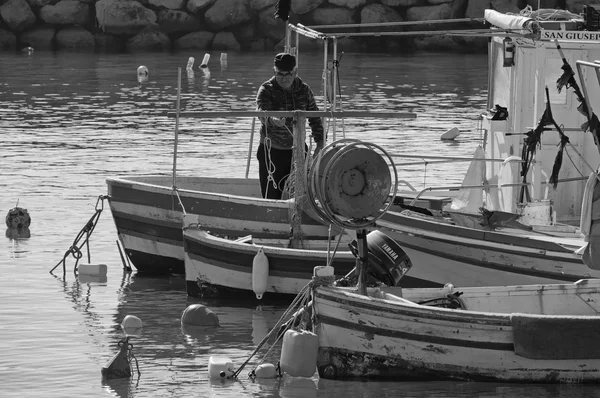 Itália, Sicília, Mar Mediterrâneo, Punta Secca (província de Ragusa); 02 fevereiro 2016, pescador trabalhando em seu barco de pesca de madeira no porto - EDITORIAL — Fotografia de Stock