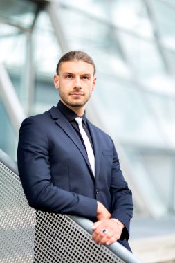 Yakışıklı, şık, genç bir iş adamı. Açık havada poz veriyor.