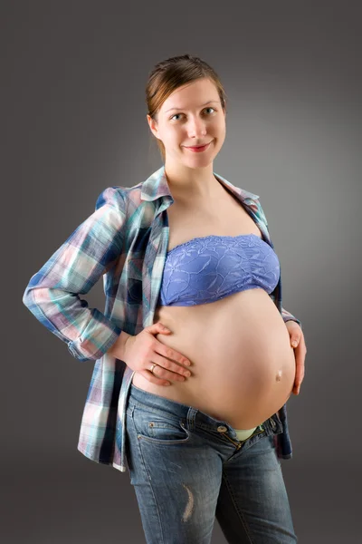Těhotná žena na šedém pozadí — Stock fotografie