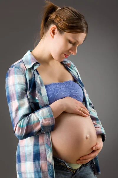 Zwangere vrouw op grijze achtergrond — Stockfoto