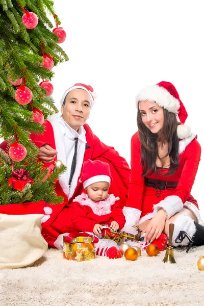幸福的家庭，在圣诞节前夕在家里坐在靠近装饰的枞树 — 图库照片