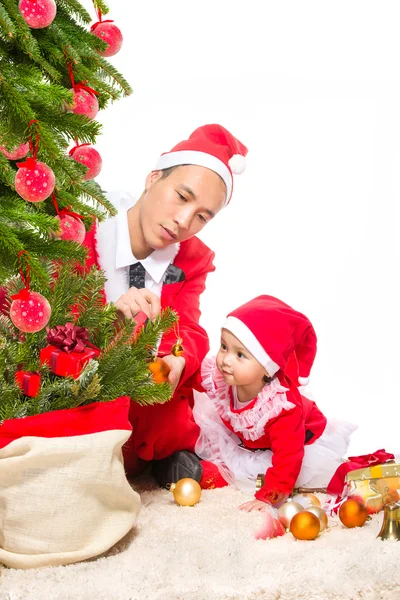 クリスマスイブに幸せな家族は自宅内装のモミの木のそばに座ってください。 ストックフォト