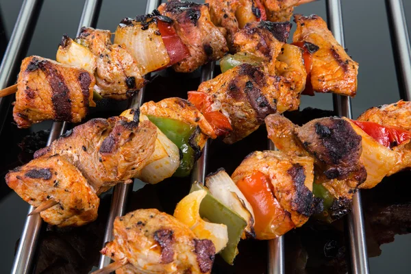 Grilled shaslik skewers on a cooking grate with reflections on a — Stock Photo, Image