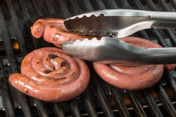 Circled sausages on a grill. One sausage is going for a turn by — Stock Photo, Image