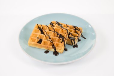İki Belçikalı waffle üzerine beyaz izole bir blueish tabakta çikolata ile