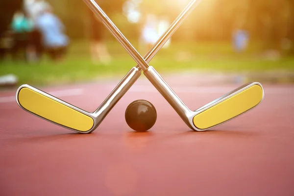 Cenário de Minigolf consistem de duas raquetes de minigolfe cruzadas e uma bola com flares de lente — Fotografia de Stock