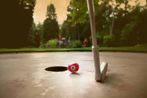 Jogador de minigolfe tenta colocar uma pequena bola de bilhar no buraco — Fotografia de Stock