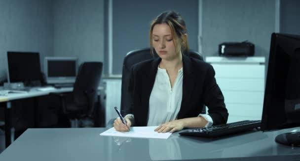 4K: Estresse no escritório. Uma mulher trabalha em uma pilha de documentos e esperanças para o fim do trabalho. O chefe coloca sua nova pilha na mesa . — Vídeo de Stock