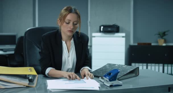 4K: Um jovem secretário está classificando e arquivando alguns documentos no escritório — Vídeo de Stock