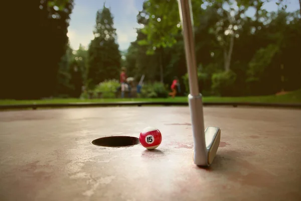 Minigolf jugador trata de poner una pequeña bola billar con el número quince Fotos de stock