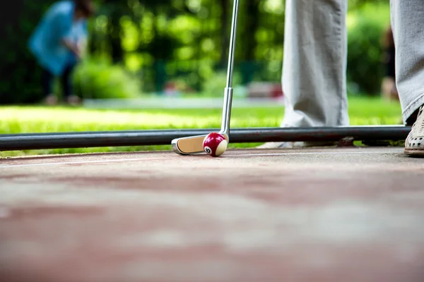 Minigolf player tries to put a small looking billard cue ball — Stock Photo, Image