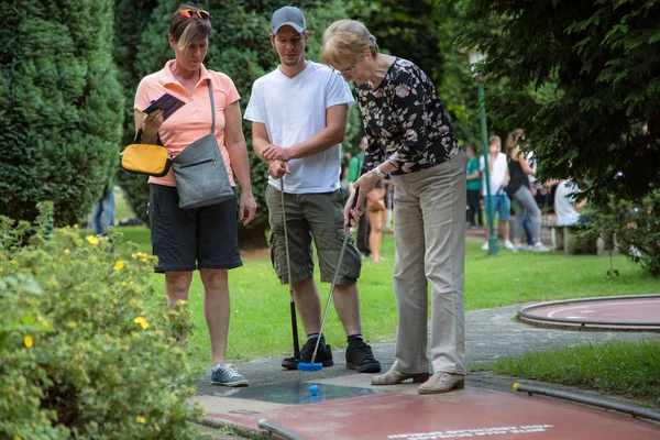 Tři generace rodiny zahrát minigolf. — Stock fotografie