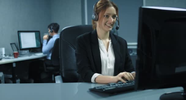 4k: δύο γυναίκες callcenter πράκτορες εργάζονται στο τον υπολογιστή με ένα ακουστικό. — Αρχείο Βίντεο