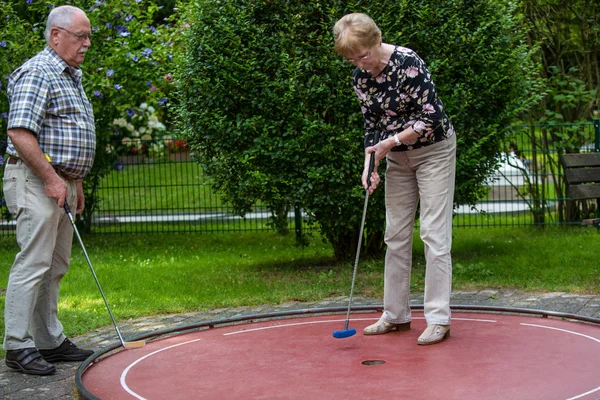 Two pensioners at a minigolf court playing minigolf — Stock Photo, Image