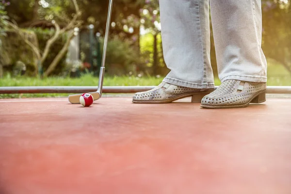 Giocatore di minigolf inizia a colpire un biliardo guardando palla da stecca Foto Stock Royalty Free