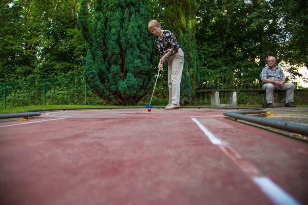 Dos pensionistas en una cancha de minigolf jugando al minigolf Imágenes de stock libres de derechos