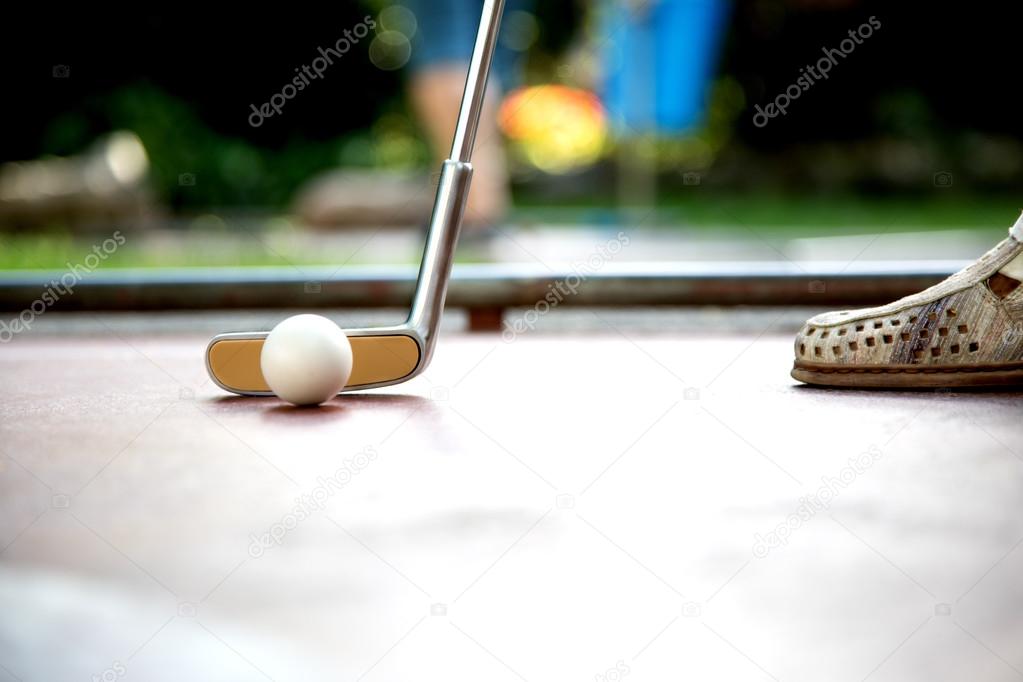 Closeup view from a professional minigolf player hitting a white ball