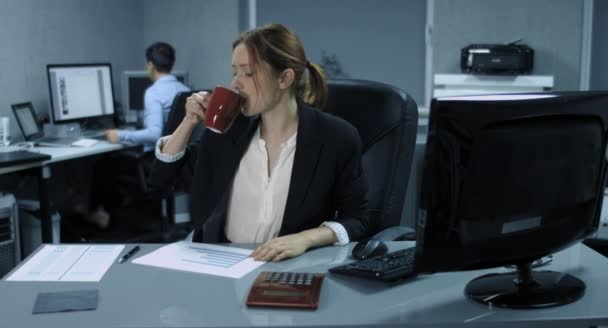 4k: dvě ženské úředníci pracují v kanceláři. Mladá žena kontrolované klidně nějaké dokumenty a pití kávy