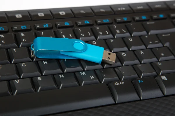 Vara USB azul em um teclado, isolado no branco — Fotografia de Stock