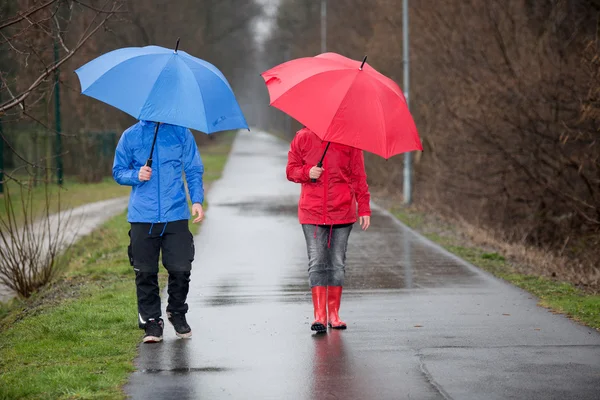 A raincoat dressed couple walking in the rain — Stock Photo, Image